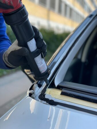 Technician applying adhesive for auto glass repair in Baytown, windshield repair checklist